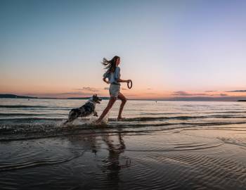 Guide to Pet-Friendly Vacations in Port Aransas: A woman running with her dog on the beach