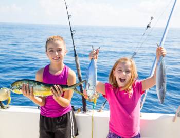 Two girls holding up fish caught on a summer fishing trip to Port Aransas, Texas