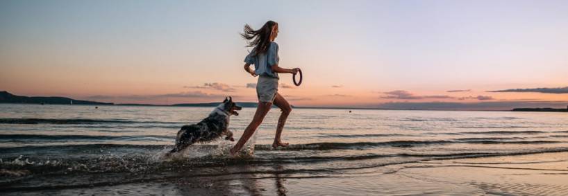 Guide to Pet-Friendly Vacations in Port Aransas: A woman running with her dog on the beach
